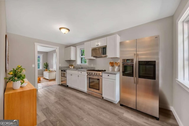 kitchen featuring light wood-type flooring, appliances with stainless steel finishes, sink, and white cabinetry