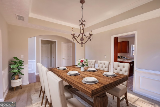 carpeted dining area with ornamental molding and a notable chandelier