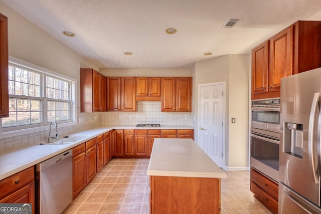 kitchen featuring backsplash, a kitchen island, sink, a textured ceiling, and stainless steel appliances