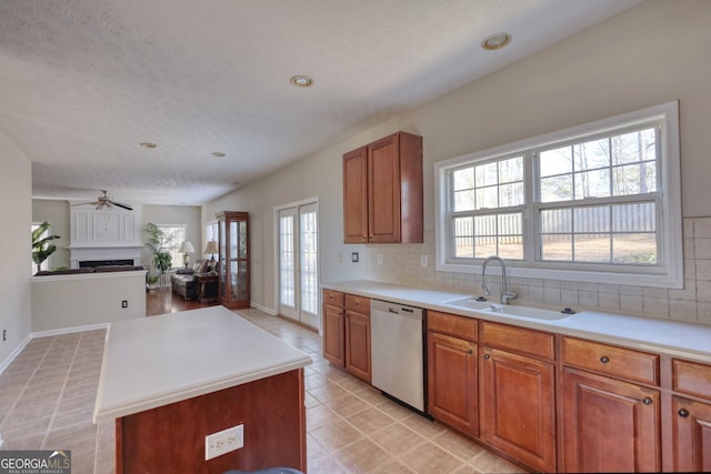 kitchen with tasteful backsplash, dishwasher, a textured ceiling, a kitchen island, and sink