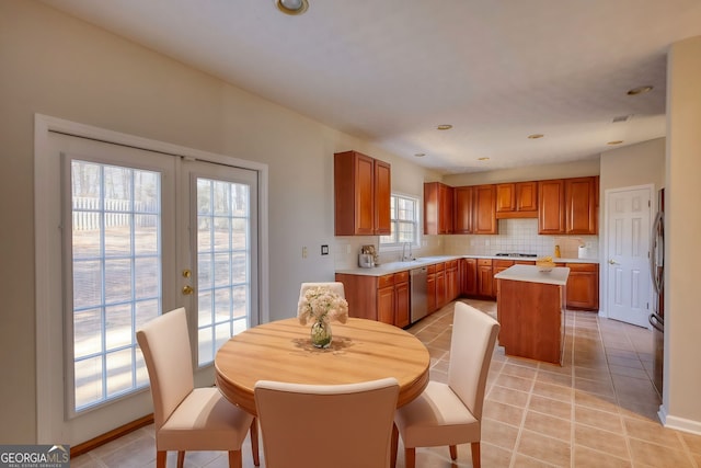 kitchen featuring a center island, stainless steel appliances, french doors, decorative backsplash, and light tile patterned flooring