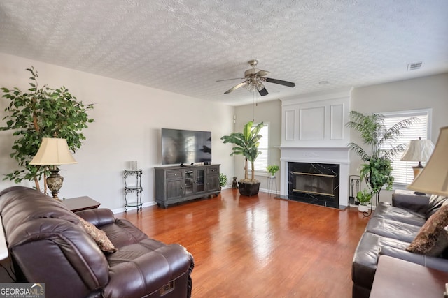 living room featuring wood-type flooring, a fireplace, and a textured ceiling