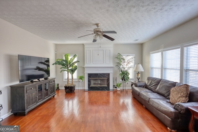 living room featuring light hardwood / wood-style floors, a textured ceiling, ceiling fan, and a fireplace