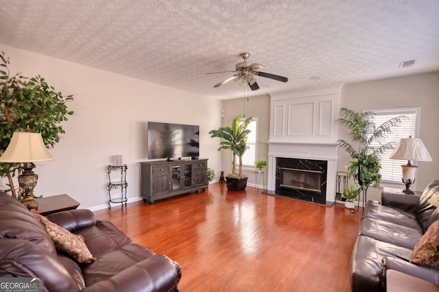 living room featuring a textured ceiling, ceiling fan, a fireplace, and hardwood / wood-style floors