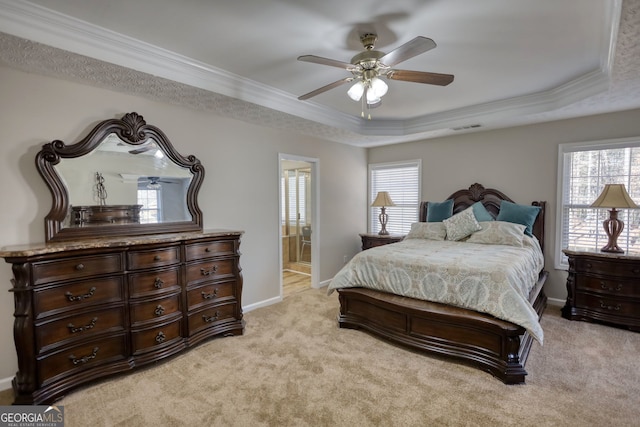 bedroom with light carpet, ceiling fan, a raised ceiling, and ensuite bath