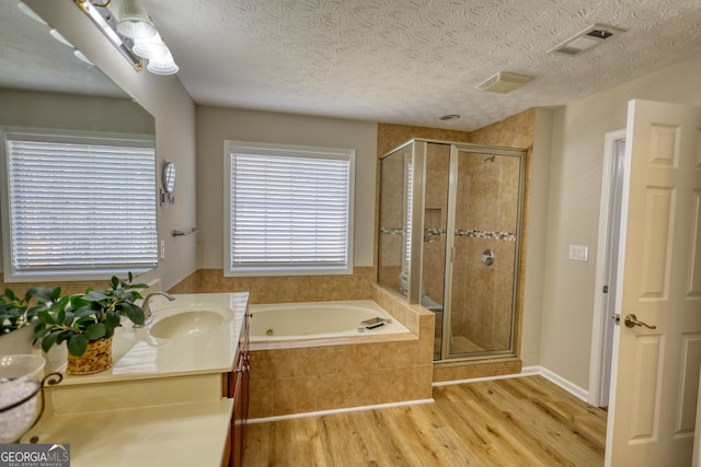 bathroom with a textured ceiling, shower with separate bathtub, hardwood / wood-style floors, and vanity