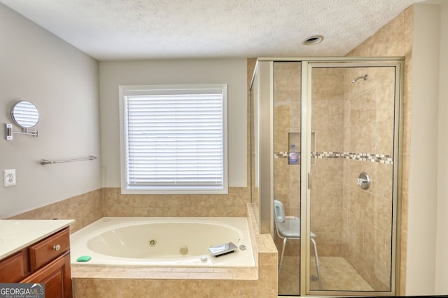 bathroom with a textured ceiling, vanity, and plus walk in shower