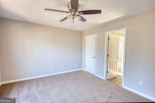 unfurnished bedroom with ceiling fan, ensuite bath, a textured ceiling, and light carpet