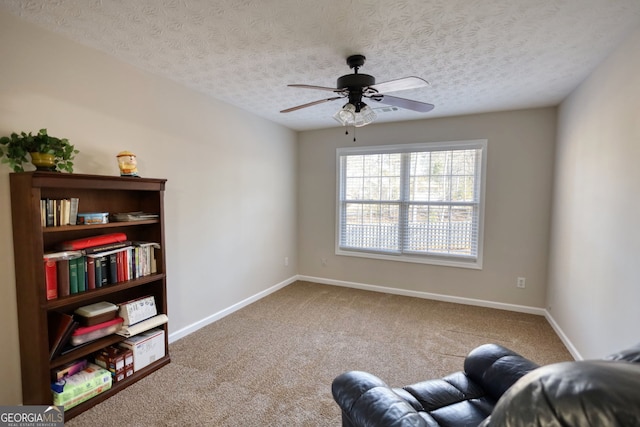 living area with ceiling fan, a textured ceiling, and carpet flooring