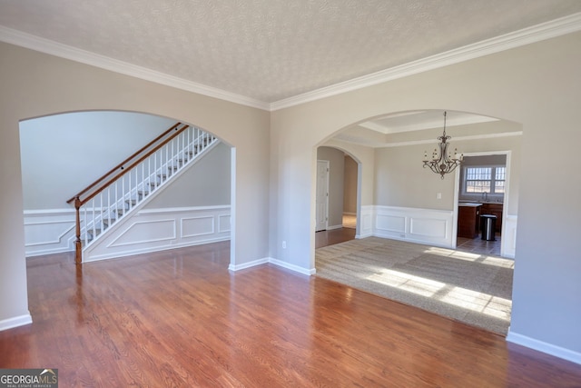 empty room with a chandelier, a tray ceiling, ornamental molding, and a textured ceiling