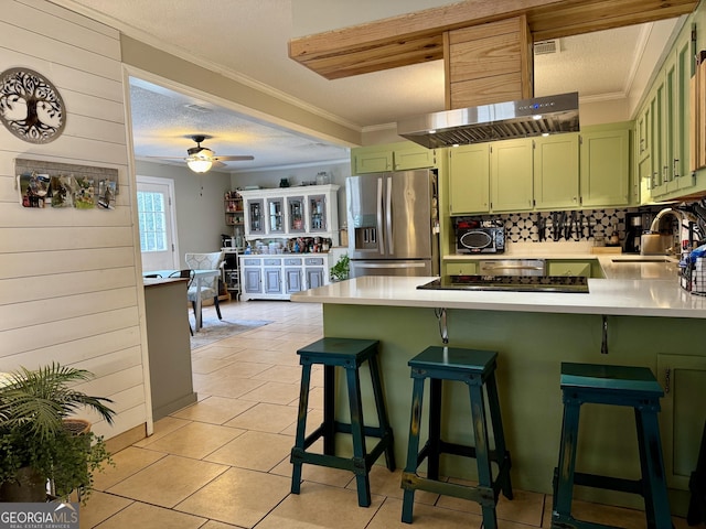 kitchen featuring a textured ceiling, stainless steel refrigerator with ice dispenser, sink, a kitchen breakfast bar, and kitchen peninsula