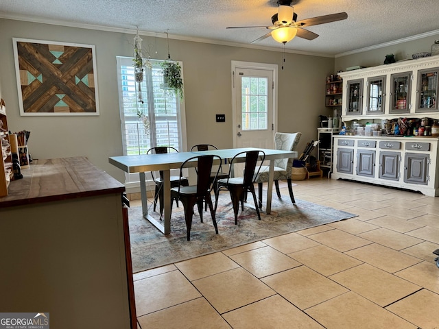 dining room with a textured ceiling, light tile patterned floors, and crown molding