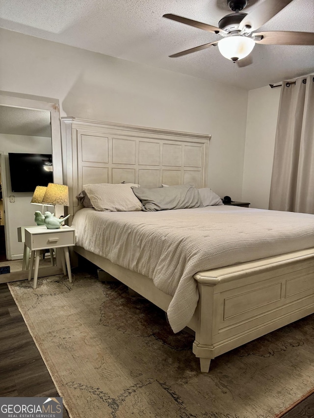 bedroom featuring ceiling fan, dark hardwood / wood-style floors, and a textured ceiling