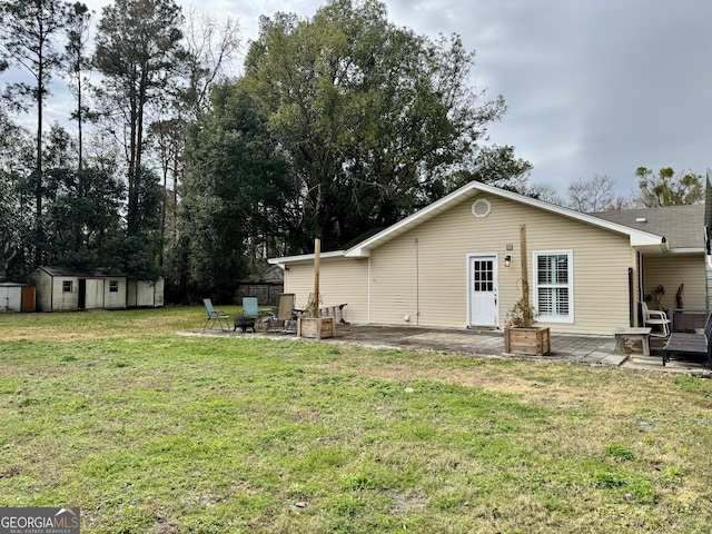 back of house featuring a lawn, a storage shed, an outdoor fire pit, and a patio area