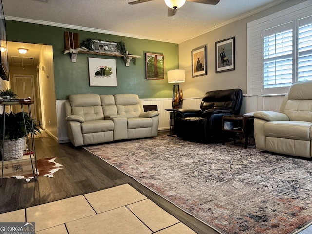 living room with ceiling fan, a textured ceiling, wood-type flooring, and crown molding