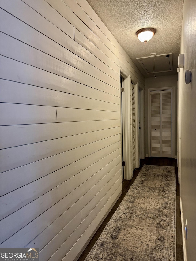 corridor with a textured ceiling and wood walls