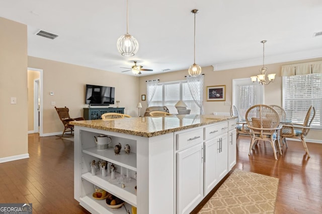 kitchen with decorative light fixtures, light stone countertops, white cabinetry, and a kitchen island