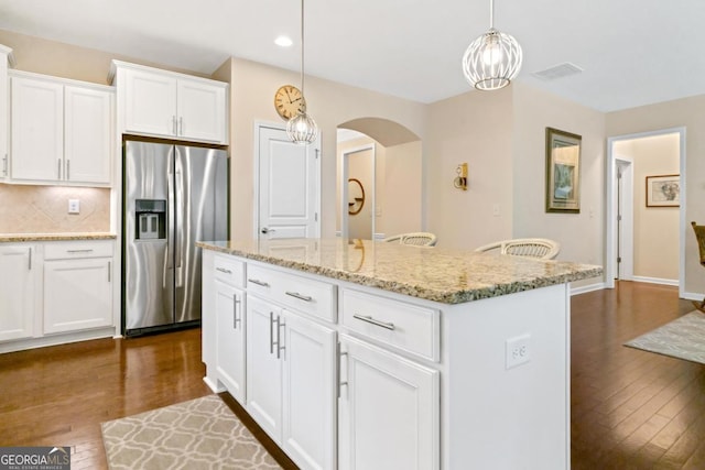 kitchen with backsplash, a center island, white cabinetry, hanging light fixtures, and stainless steel fridge