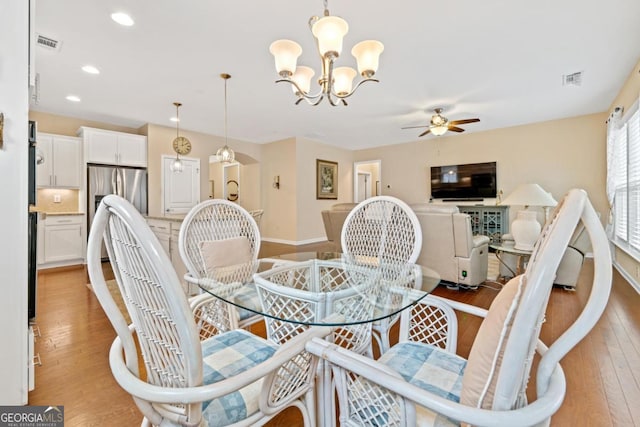 dining space with light wood-type flooring and ceiling fan with notable chandelier