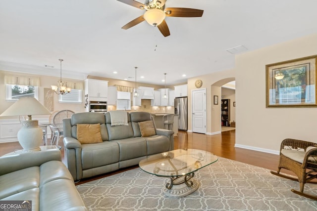 living room featuring ceiling fan with notable chandelier and wood-type flooring