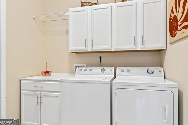 laundry area with washing machine and clothes dryer and cabinets