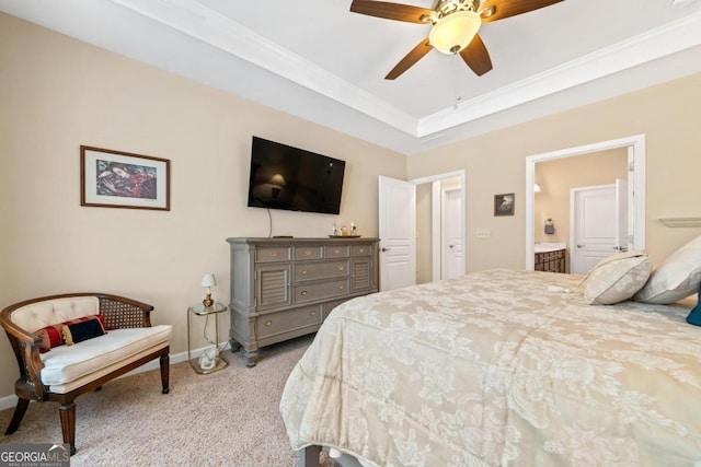 carpeted bedroom featuring ceiling fan, ensuite bath, a tray ceiling, and crown molding