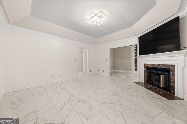 unfurnished living room with a raised ceiling, marble finish floor, baseboards, and a premium fireplace