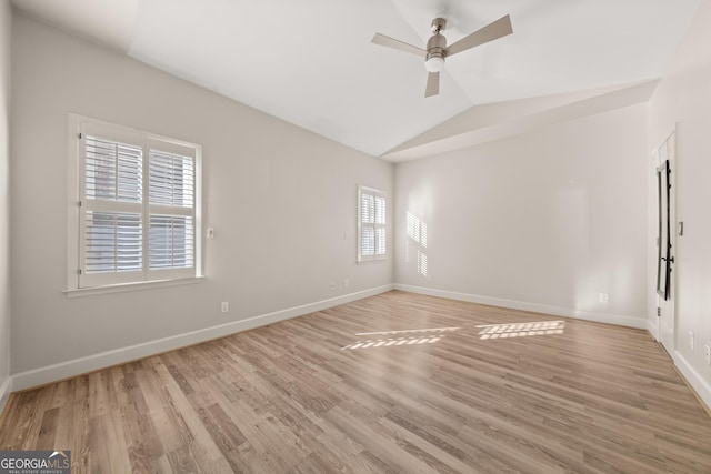 spare room with lofted ceiling, light wood-style floors, and baseboards