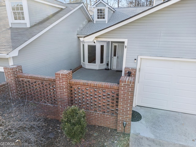 view of exterior entry featuring a shingled roof