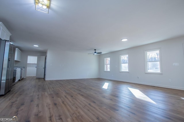 unfurnished living room featuring ceiling fan and dark wood-type flooring