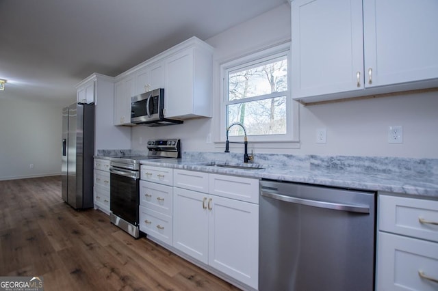 kitchen with dark hardwood / wood-style floors, sink, light stone countertops, appliances with stainless steel finishes, and white cabinets