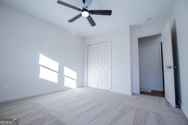 unfurnished bedroom with ceiling fan, light colored carpet, and a closet