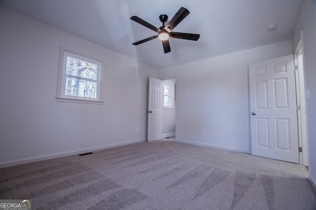 carpeted spare room with ceiling fan and plenty of natural light