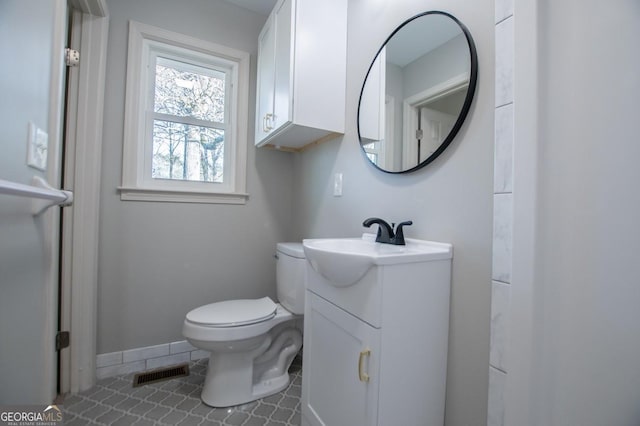 bathroom with toilet, vanity, and tile patterned flooring