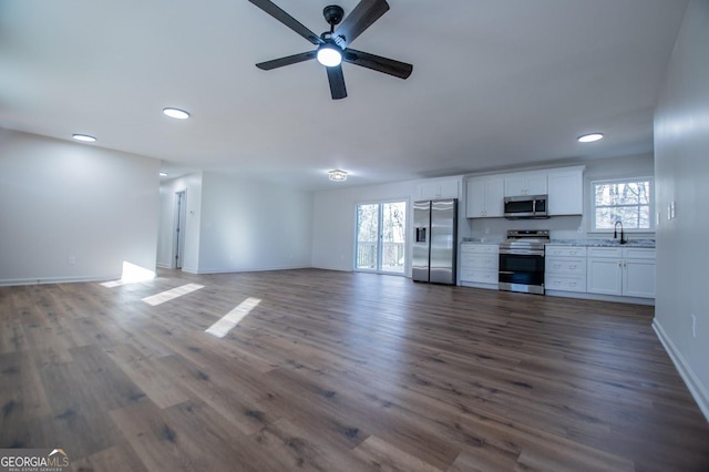 unfurnished living room with ceiling fan, sink, and dark hardwood / wood-style flooring