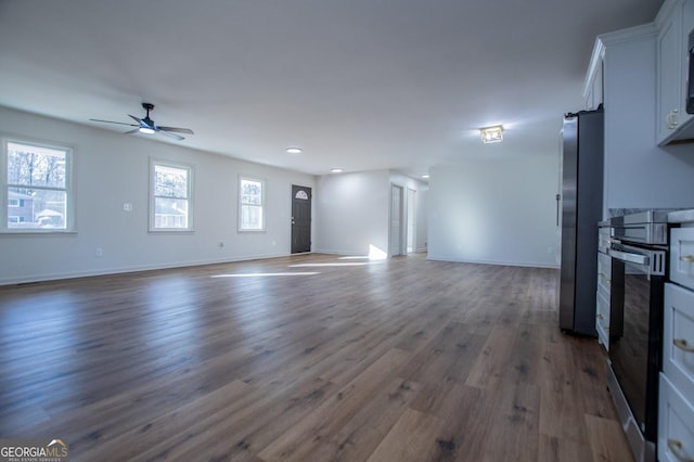 unfurnished living room with ceiling fan and dark hardwood / wood-style flooring