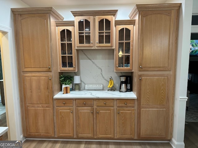 bar with tasteful backsplash, light stone counters, and light hardwood / wood-style floors