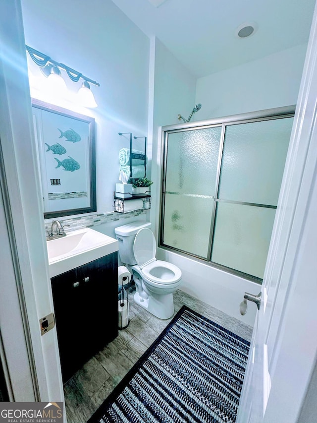 full bathroom featuring bath / shower combo with glass door, vanity, and toilet