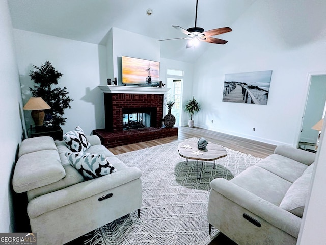 living room with a brick fireplace, wood-type flooring, high vaulted ceiling, and ceiling fan