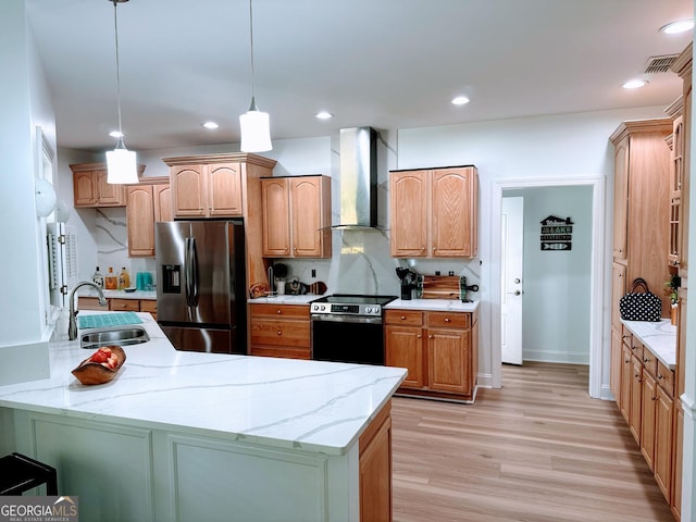 kitchen featuring sink, decorative light fixtures, stainless steel appliances, light stone countertops, and wall chimney range hood