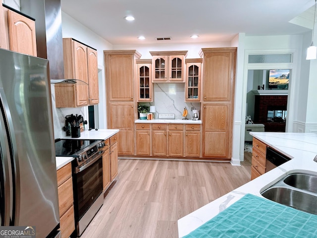 kitchen with tasteful backsplash, sink, hanging light fixtures, stainless steel appliances, and light wood-type flooring