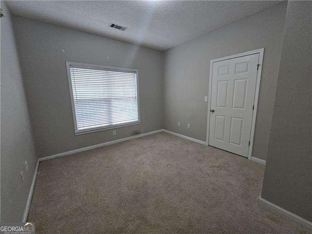 spare room featuring carpet floors and a textured ceiling