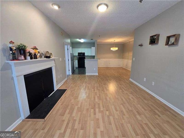 unfurnished living room with light hardwood / wood-style floors and a textured ceiling