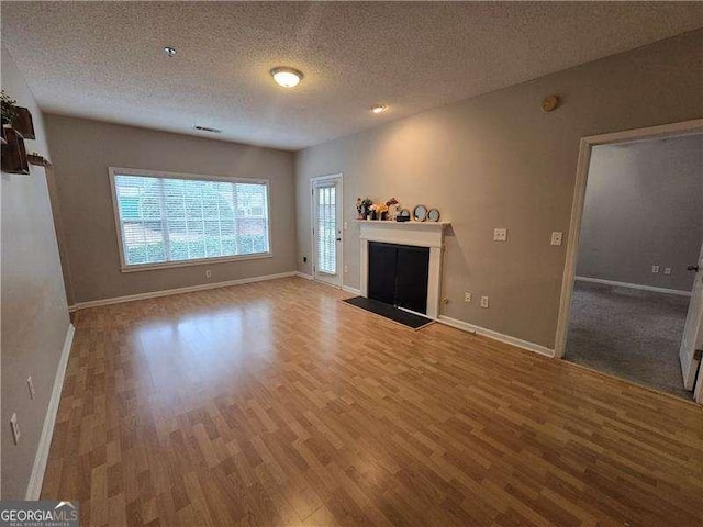 unfurnished living room with wood-type flooring and a textured ceiling