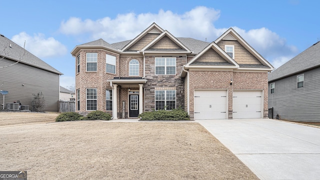 craftsman inspired home with brick siding, concrete driveway, central AC unit, a garage, and stone siding