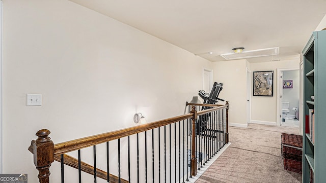 hall with attic access, baseboards, carpet flooring, and an upstairs landing