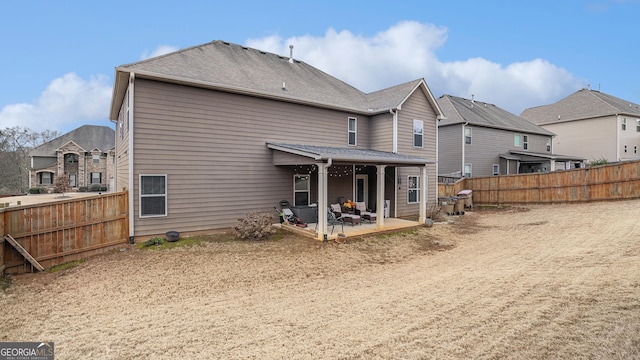 back of property with a patio, roof with shingles, a fenced backyard, and a residential view