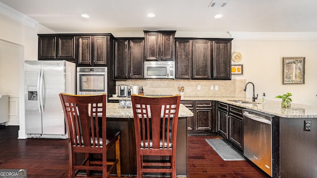 kitchen with visible vents, appliances with stainless steel finishes, ornamental molding, a sink, and a peninsula