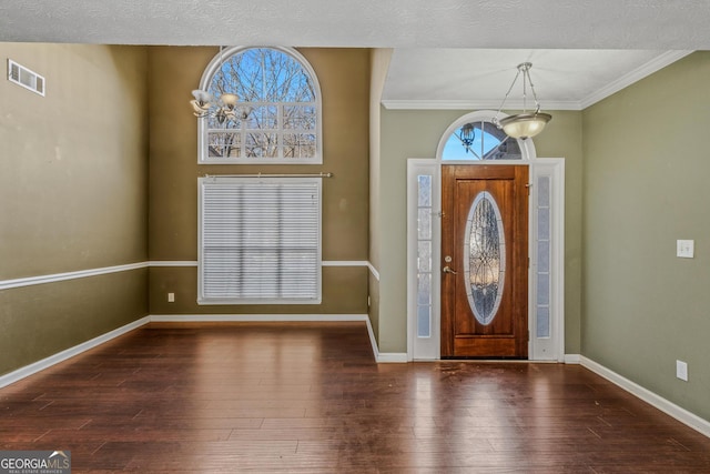 foyer featuring dark hardwood / wood-style floors, ornamental molding, and a textured ceiling