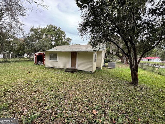 rear view of property featuring central air condition unit and a yard